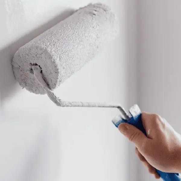 man painting wall with roller